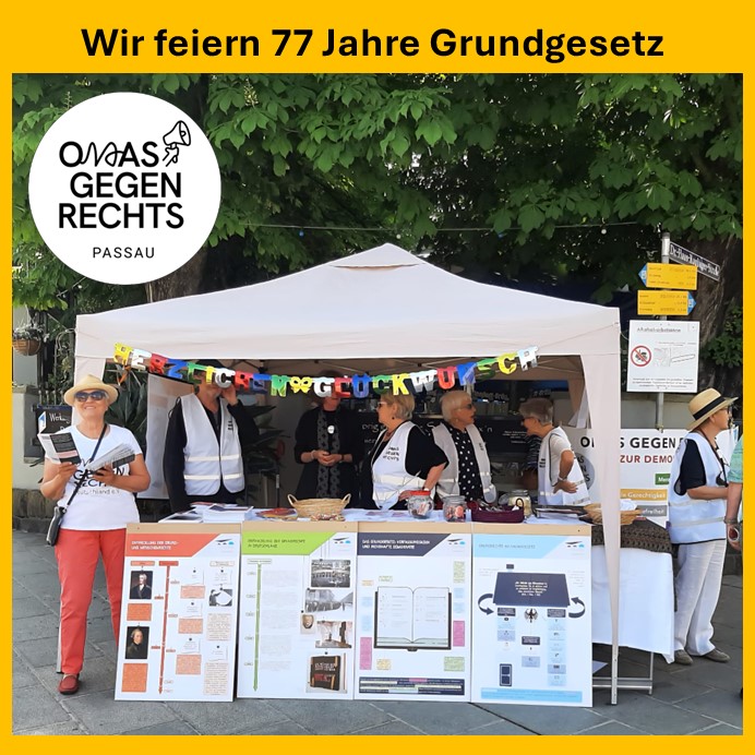 Ein Stand der Omas Gegen Rechts mit Infomaterialien vor grünen Bäumen.